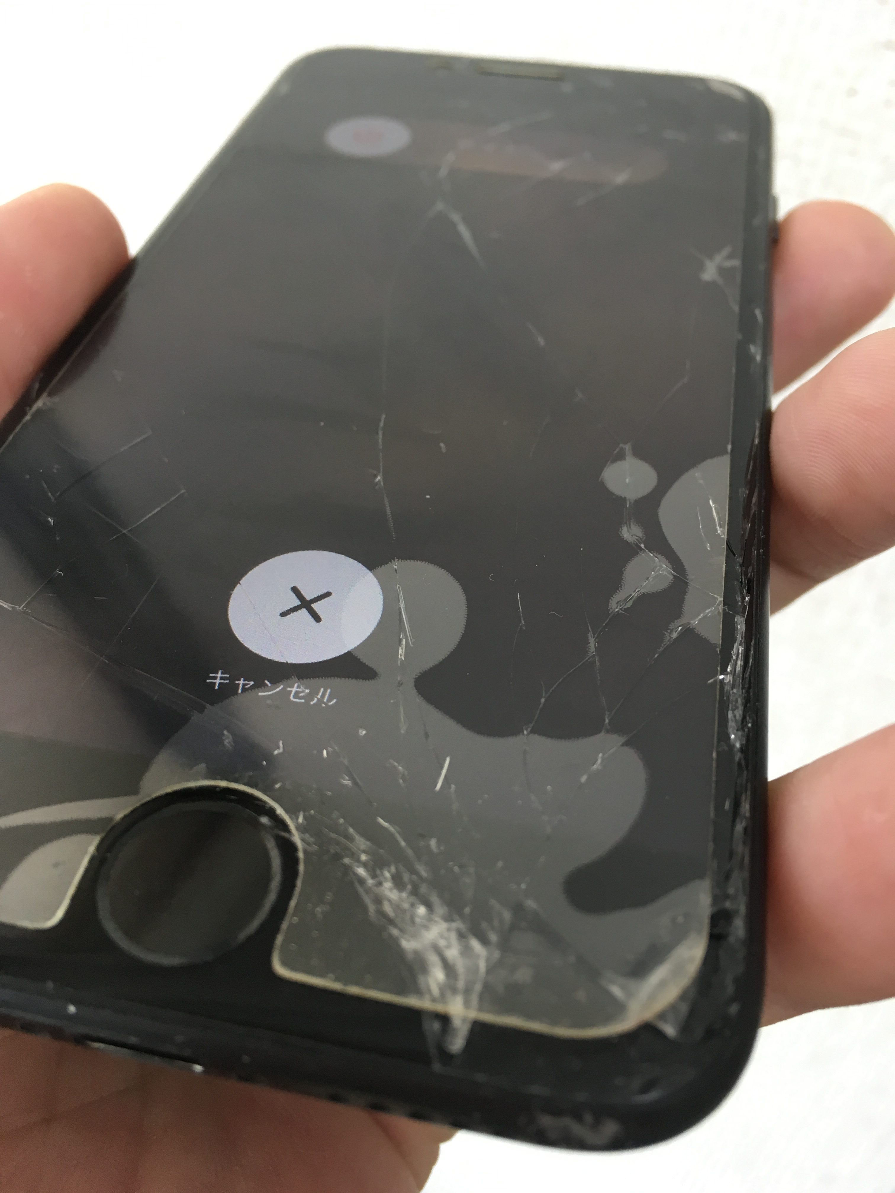 修理前：ガラスが割れて穴が開いたiPhone7